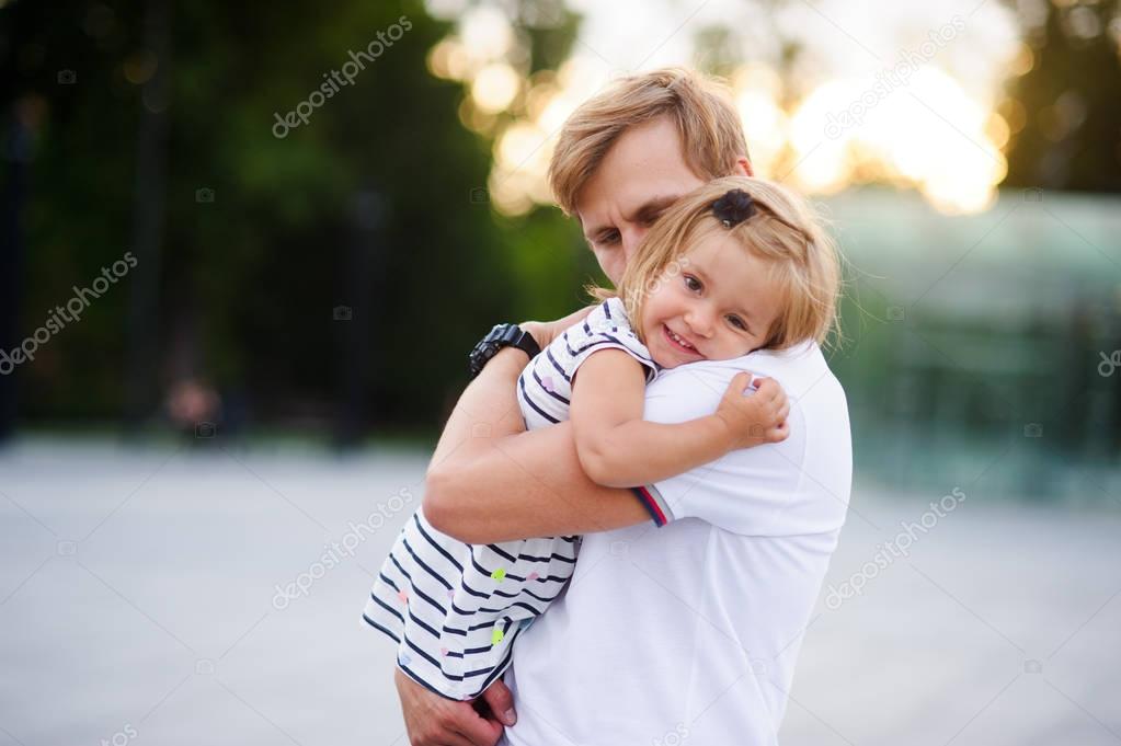 Young father holds the little daughter on hands.