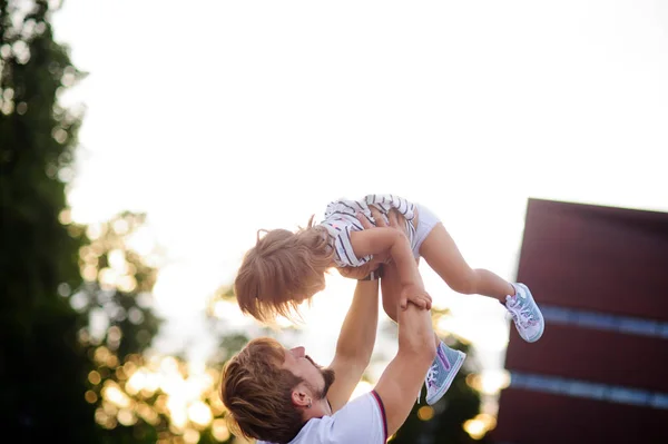 O pai jovem mantém a filha pequena a mãos . — Fotografia de Stock