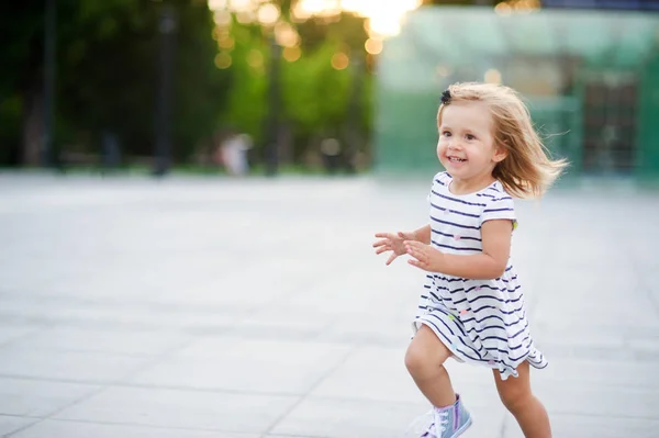 Nettes kleines Mädchen läuft über den Platz im Stadtpark. — Stockfoto