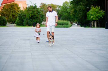 Bir köpek parkta yürüyüş küçük kızı olan baba.