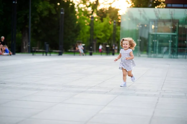 Sevimli küçük kız bir şehir parkı meydanda etrafında çalışır. — Stok fotoğraf