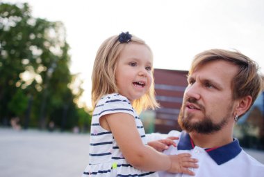 Genç baba küçük kızı ellerinde tutar..