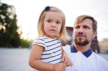 Genç baba küçük kızı ellerinde tutar..