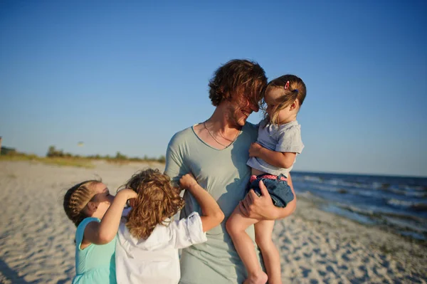 Ο μπαμπάς παίζει στην παραλία με τρία παιδιά. — Φωτογραφία Αρχείου