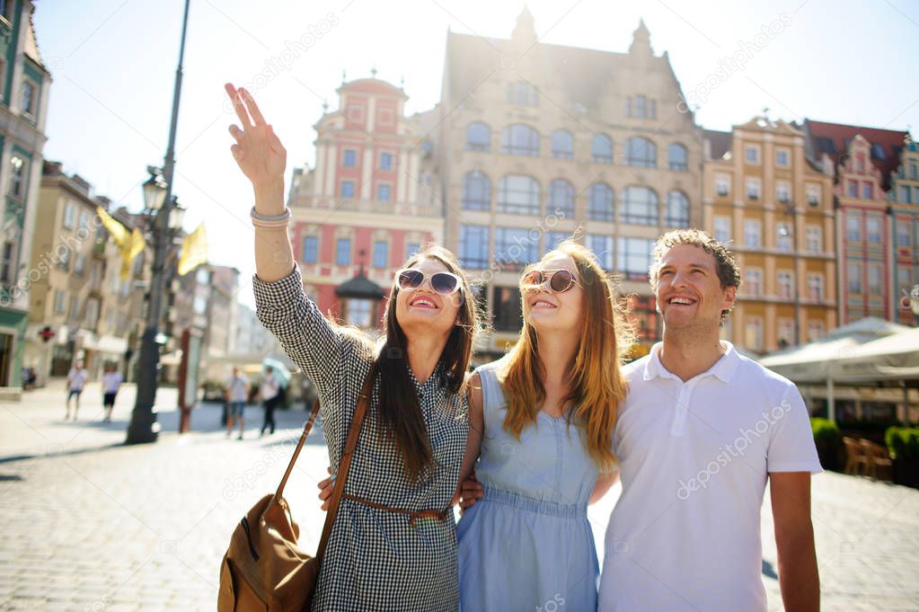 Three young people stand on the square of the ancient city.