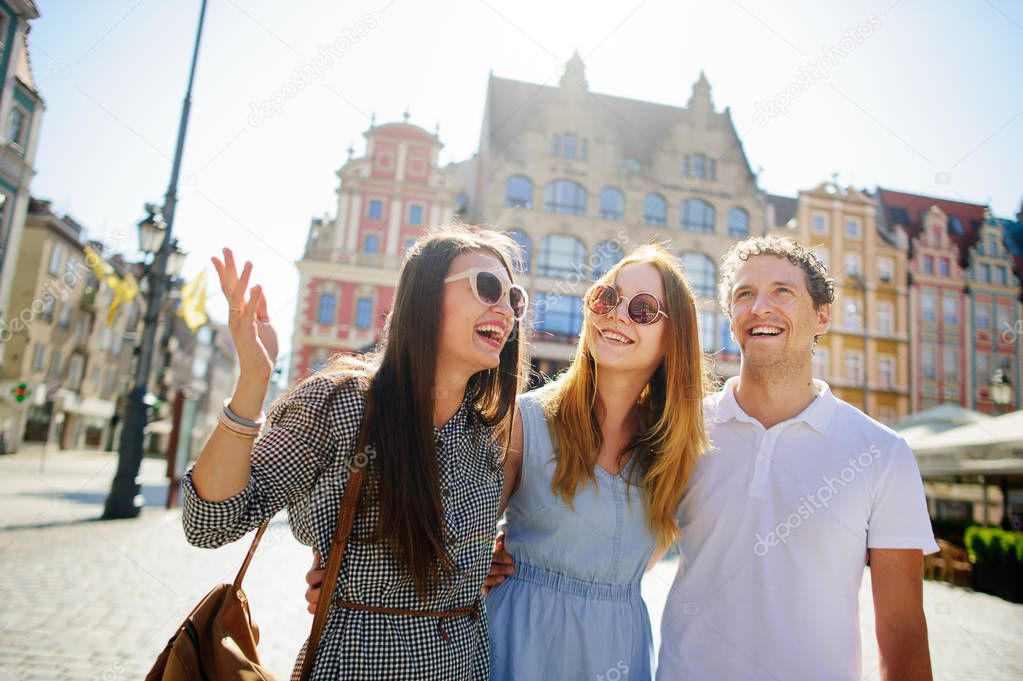 Three young people stand on the square of the ancient city.