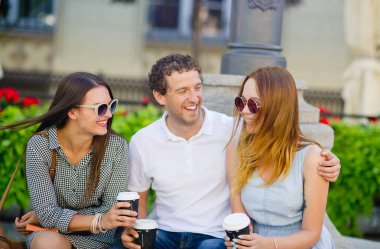 İki hatun ve bir adam kahve içme ve canlı konuşuyor.