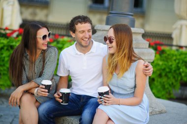 İki hatun ve bir adam kahve içme ve canlı konuşuyor.