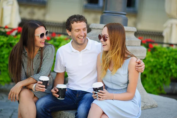 İki hatun ve bir adam kahve içme ve canlı konuşuyor.