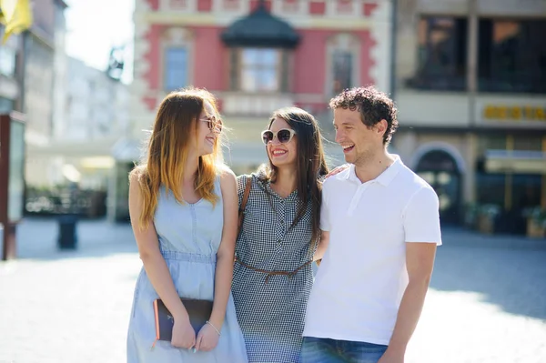 Three young people stand on the square of the ancient city. — Stock Photo, Image