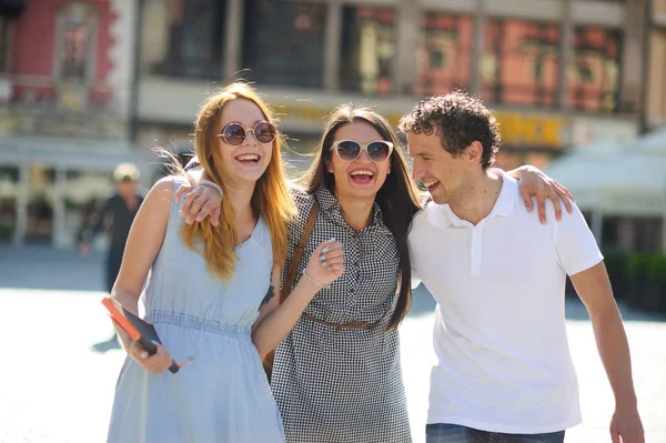 Drie jonge mensen staan op het plein van de oude stad. — Stockfoto