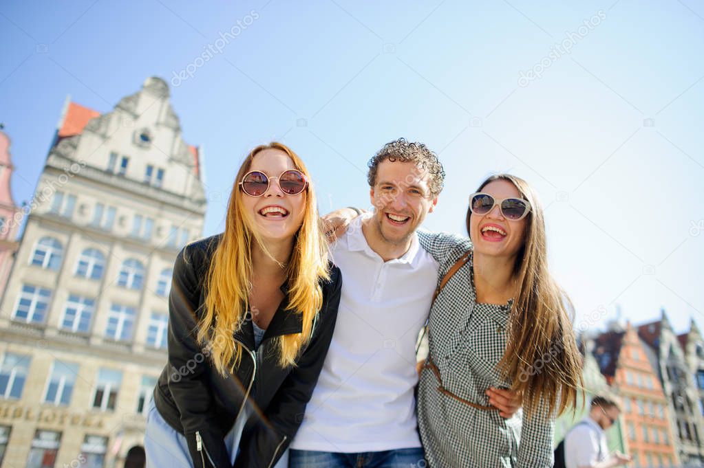 Three young people stand on the square of the ancient city.