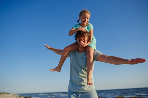 Молодой человек весело проводит время с маленькой дочкой у моря . — стоковое фото