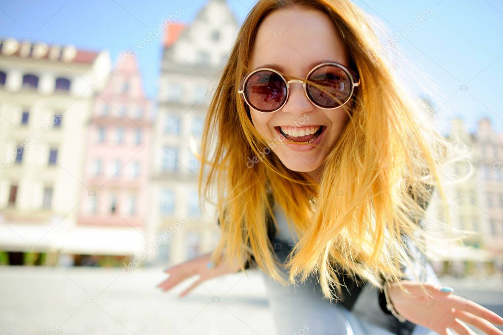 Charming young girl in sunglasses against the backdrop of a beautiful old building.