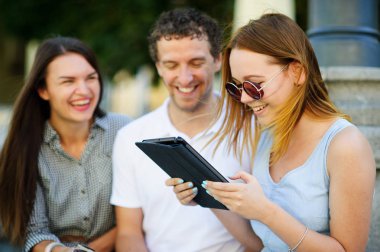 İki hatun ve ilgi ile adam tablet ekrana bak.