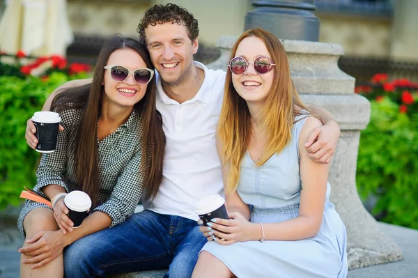 İki hatun ve bir adam kahve içme ve canlı konuşuyor.