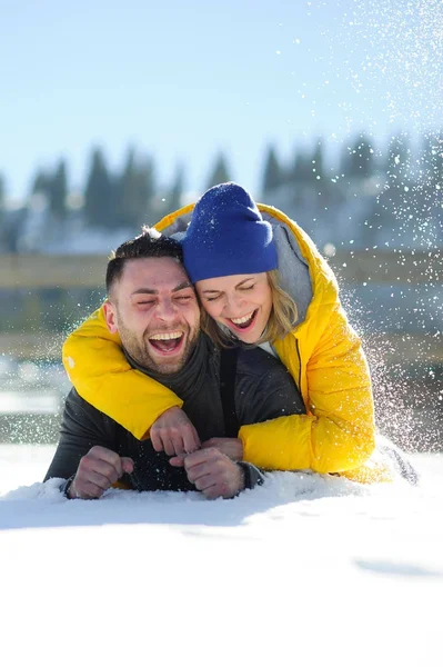 Cheerful young couple lies on snow. — Stock Photo, Image