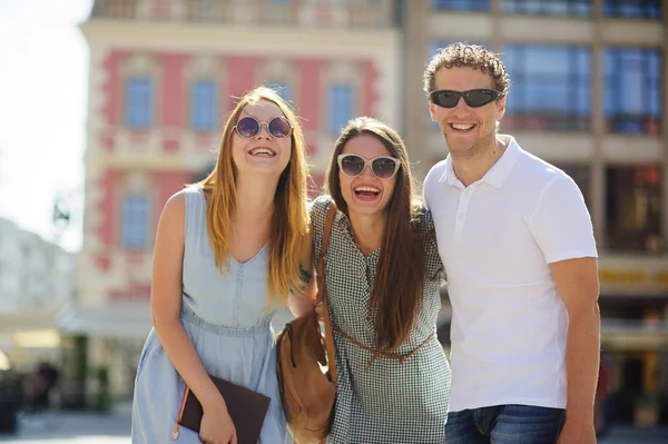 Three young people stand on the square of the ancient city. — Stock Photo, Image