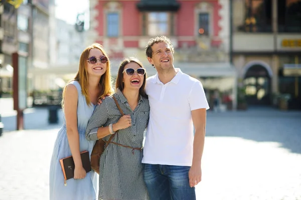 Three young people stand on the square of the ancient city. — Stock Photo, Image