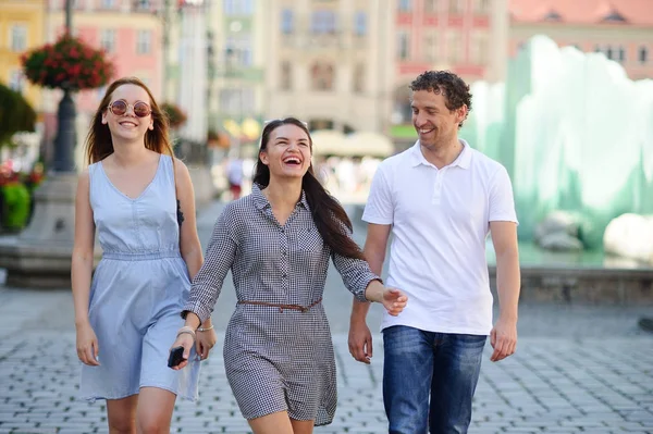 Drie jonge mensen staan op het plein van de oude stad. — Stockfoto