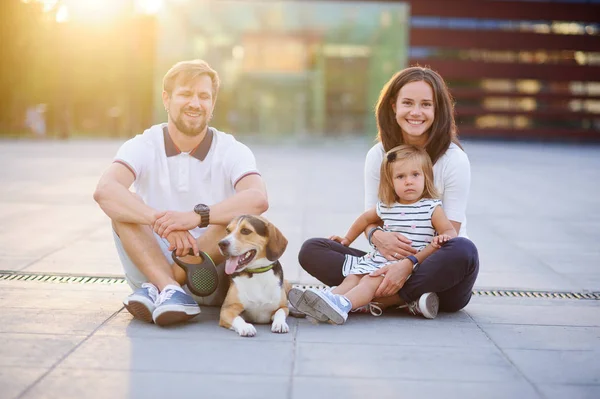 Wonderful young family is resting sitting on the ground.