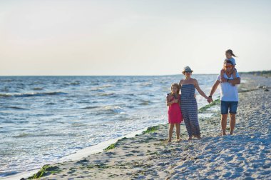 Mutlu aile el ele tutuşarak sahil yürür.