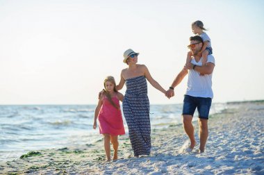 Mutlu aile el ele tutuşarak sahil yürür.