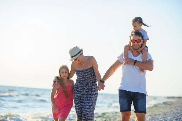 Ευτυχισμένη οικογένεια περιπάτους κατά μήκος της παραλίας, κρατώντας τα χέρια. — Φωτογραφία Αρχείου