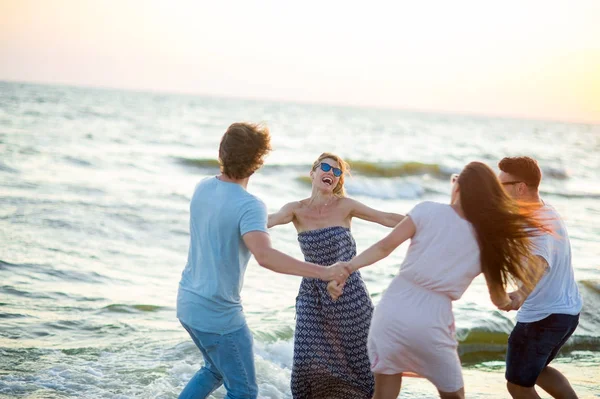 Grupo de jóvenes alegres baila habiendo unido las manos en la playa . — Foto de Stock