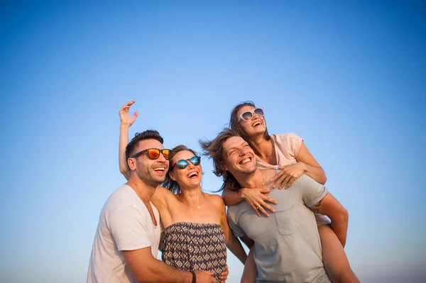 Cuatro jóvenes alegres en el fondo del cielo azul . — Foto de Stock