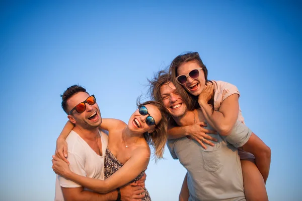 Cuatro jóvenes alegres en el fondo del cielo azul . — Foto de Stock
