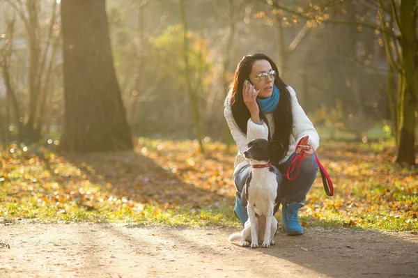 Mujer joven paseando con su perro en otoño Park . — Foto de Stock