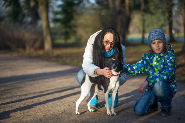 Madre e hijo pasean a su mascota en el parque de otoño . — Foto de Stock