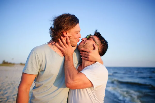 Twee mannen omarmen tegen de achtergrond van de zee. — Stockfoto