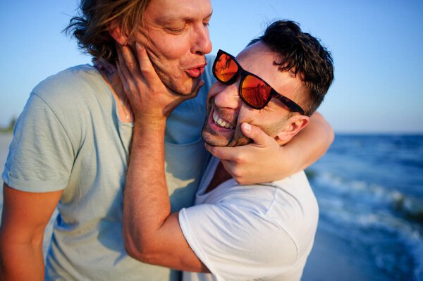 Two men embrace against the background of the sea.