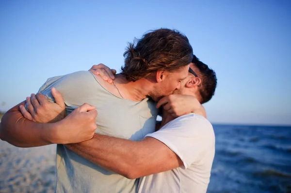 Two men embrace against the background of the sea. — Stock Photo, Image