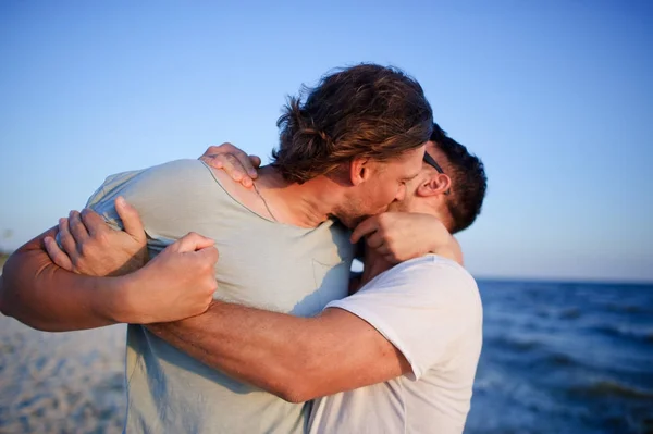 Twee mannen omarmen tegen de achtergrond van de zee. — Stockfoto