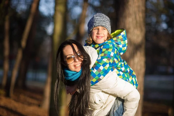 Jonge vrouw draagt op een rug van de jongen van 9-10 jaar. — Stockfoto