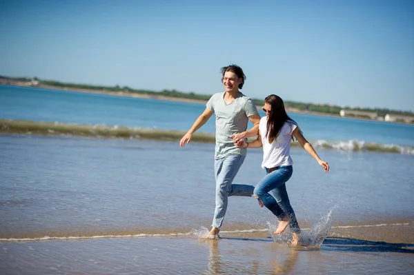 The guy and the girl running along barefoot by the water. — Stock Photo, Image