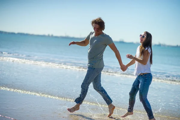 Happy couple running barefoot in the water. — Stock Photo, Image