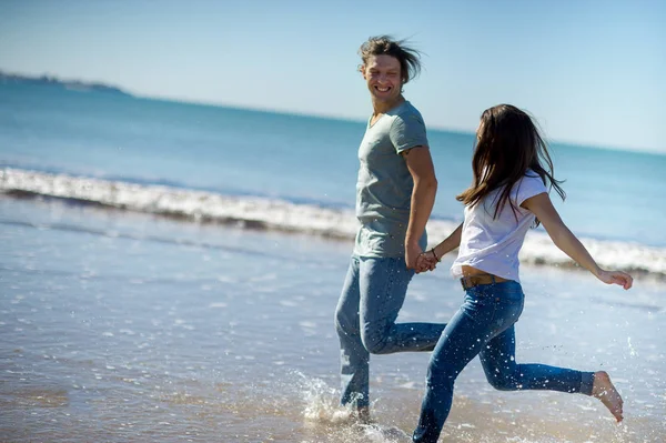 The guy and the girl running along barefoot by the water. — Stock Photo, Image