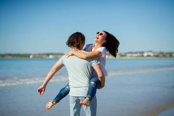 Na beira-mar o cara segura a garota em mãos . — Fotografia de Stock