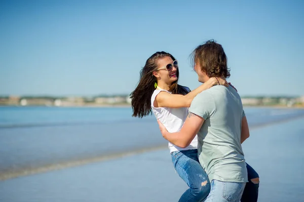 Aan de kust heeft de man het meisje op handen. — Stockfoto