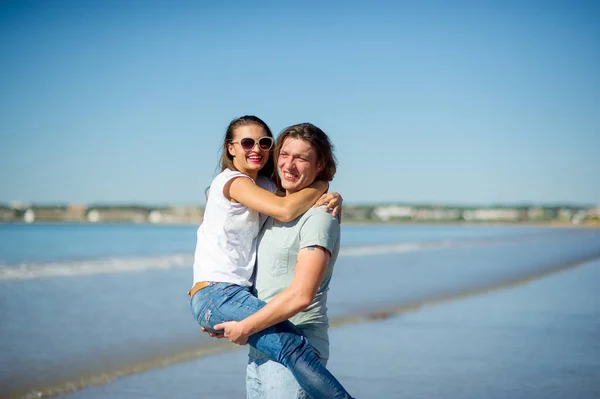 Aan de kust heeft de man het meisje op handen. — Stockfoto