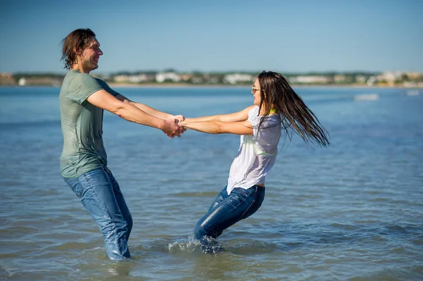 Happy young couple dances in the sea.