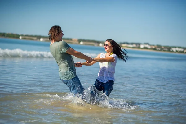 Happy young couple dances in the sea.