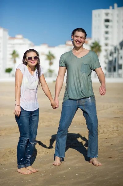 Cheerful young couple costs in wet clothes on the beach. — Stock Photo, Image