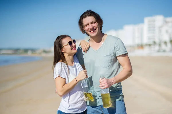 Cheerful young couple drinks wine on the beach. — Stock Photo, Image
