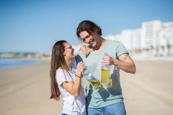 Vrolijke jonge paar alcohol wijn op het strand. — Stockfoto