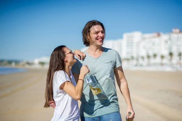 Cheerful young couple drinks wine on the beach. — Stock Photo, Image